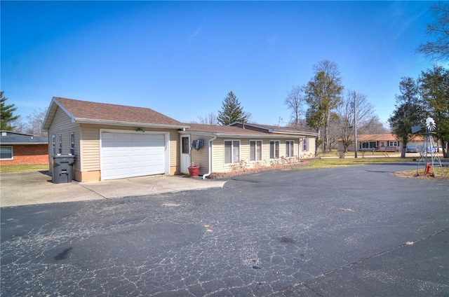 ranch-style house with aphalt driveway and an attached garage