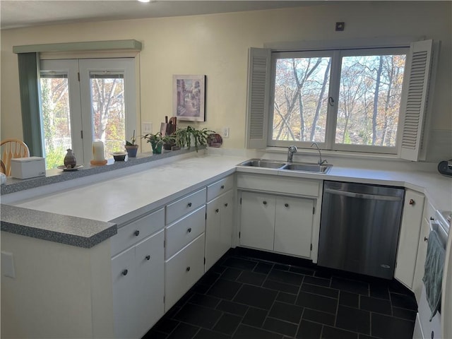 kitchen with white cabinets, kitchen peninsula, stainless steel dishwasher, and sink