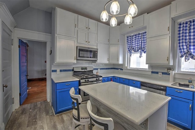 kitchen featuring decorative light fixtures, a kitchen island, wood-type flooring, stainless steel appliances, and blue cabinets