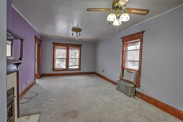 carpeted empty room featuring plenty of natural light, cooling unit, radiator heating unit, and a fireplace