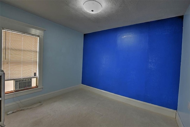 unfurnished room featuring cooling unit, a textured ceiling, and carpet flooring