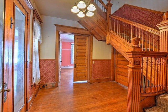 stairway with hardwood / wood-style floors, a wealth of natural light, and an inviting chandelier