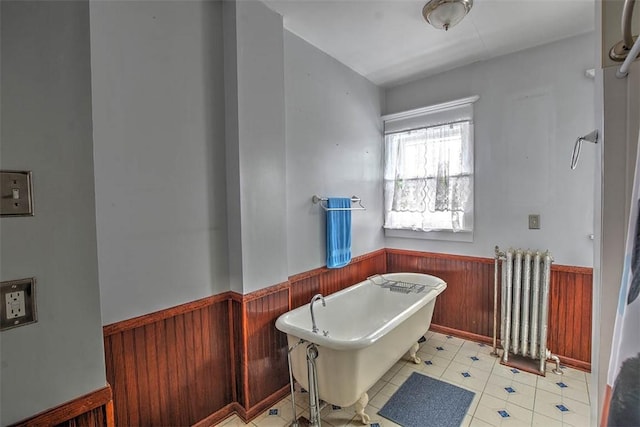 bathroom featuring a bathing tub, wood walls, and radiator heating unit