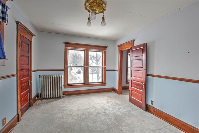 spare room with radiator and light colored carpet