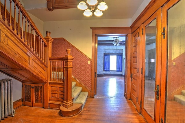 stairs featuring radiator, an inviting chandelier, and hardwood / wood-style floors