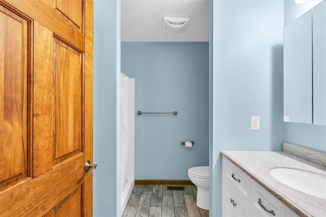 bathroom with hardwood / wood-style floors, vanity, toilet, and walk in shower