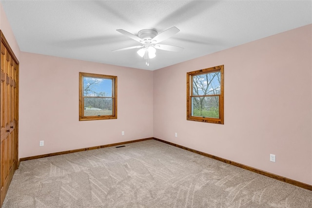 empty room with ceiling fan, light colored carpet, a textured ceiling, and a wealth of natural light