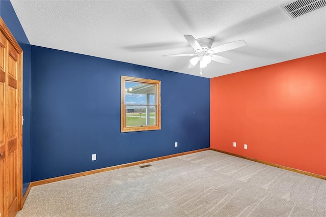 carpeted empty room featuring ceiling fan and a textured ceiling