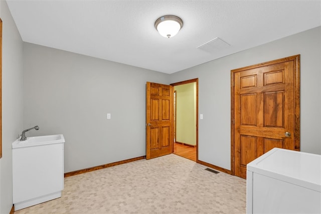 clothes washing area with a textured ceiling, sink, and washer / clothes dryer