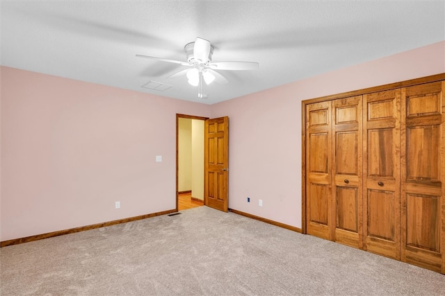 unfurnished bedroom featuring ceiling fan, light colored carpet, and a closet