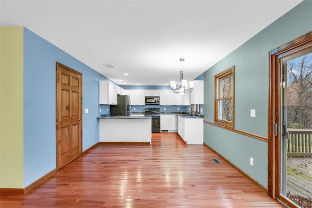 kitchen featuring white cabinets, decorative light fixtures, stainless steel appliances, and plenty of natural light