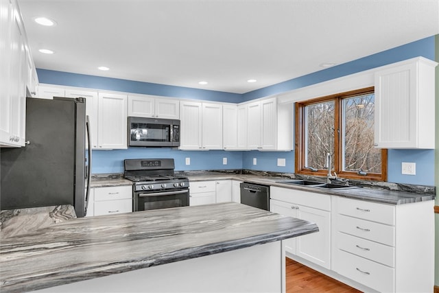 kitchen featuring white cabinetry, sink, appliances with stainless steel finishes, and light hardwood / wood-style flooring