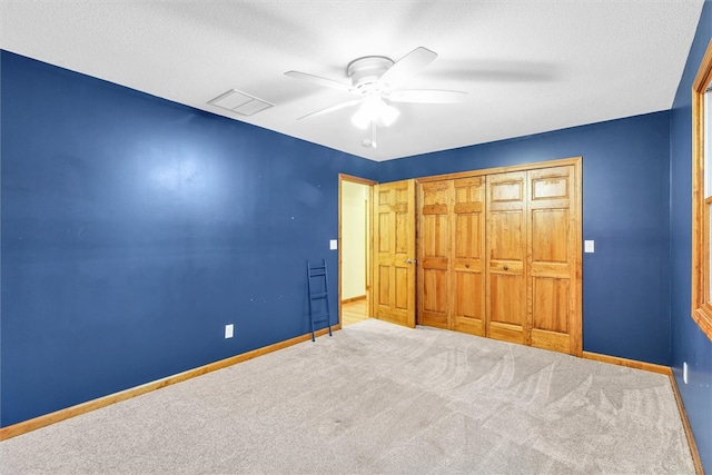 unfurnished bedroom featuring ceiling fan, carpet floors, a textured ceiling, and a closet