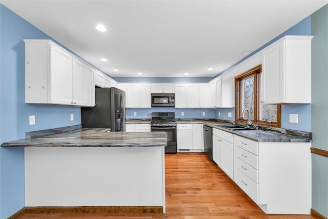 kitchen featuring sink, white cabinetry, appliances with stainless steel finishes, light hardwood / wood-style floors, and kitchen peninsula