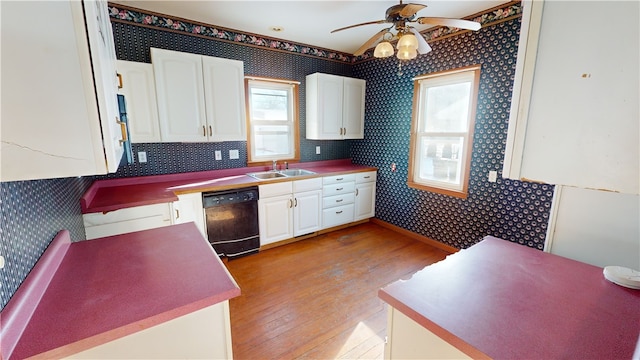 kitchen with sink, light hardwood / wood-style flooring, ceiling fan, black dishwasher, and white cabinetry