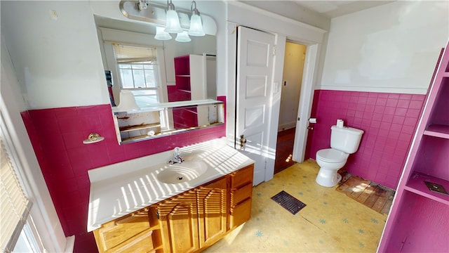 bathroom with vanity, toilet, and tile walls