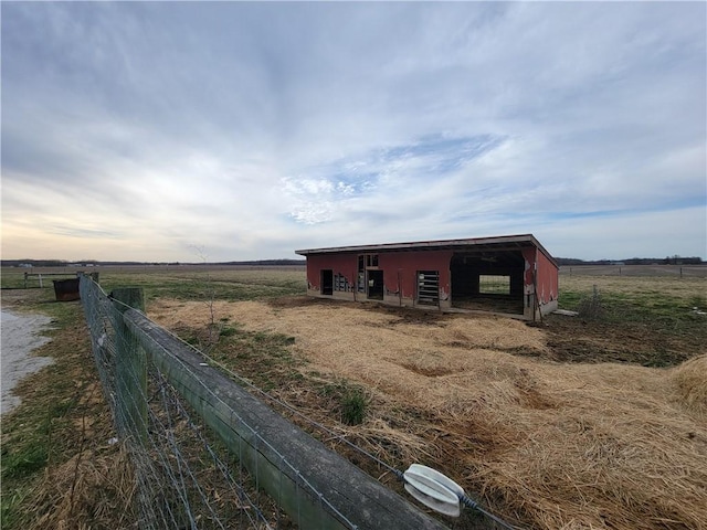 view of pole building with fence and a rural view