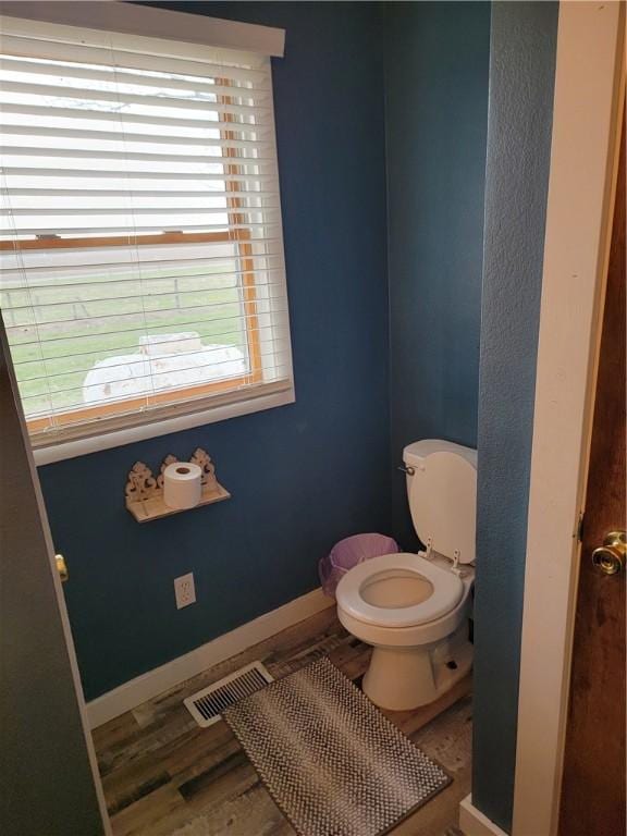 bathroom with baseboards, visible vents, toilet, and wood finished floors