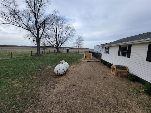 view of yard with a rural view, fence, and an outdoor structure