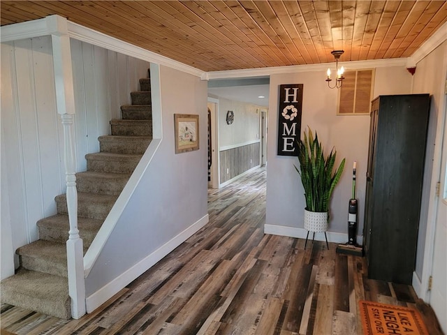 stairs with visible vents, baseboards, ornamental molding, wood finished floors, and wooden ceiling