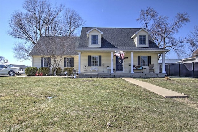 new england style home featuring roof with shingles, a porch, and a front yard