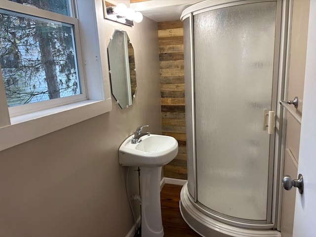 bathroom featuring wood walls, plenty of natural light, a shower with shower door, and hardwood / wood-style flooring