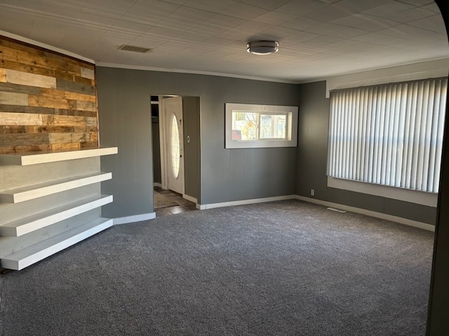 carpeted spare room with ornamental molding and wood walls