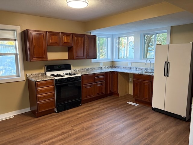 kitchen featuring light stone counters, sink, dark wood-type flooring, and white appliances