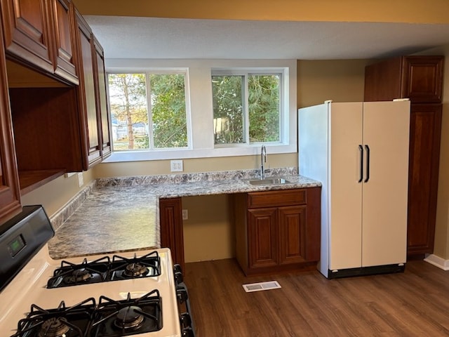 kitchen with light stone counters, sink, dark wood-type flooring, and white appliances
