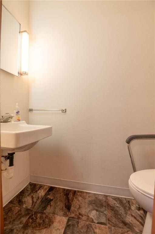 bathroom with toilet and baseboards