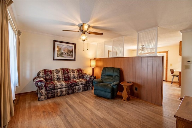 living room featuring ceiling fan, ornamental molding, and wood finished floors