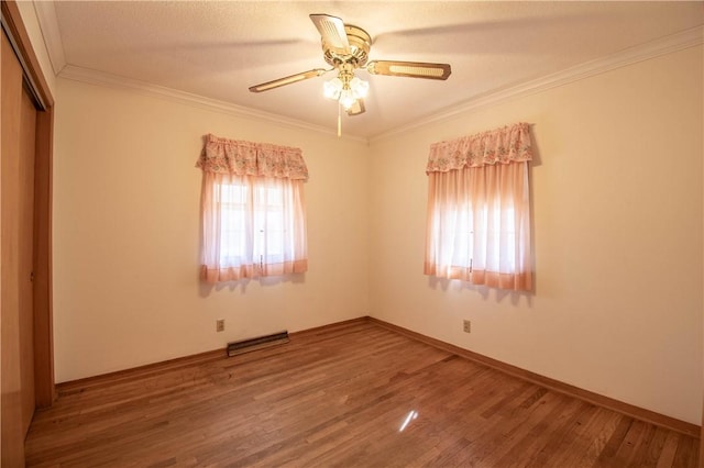 unfurnished bedroom featuring crown molding, a closet, visible vents, wood finished floors, and baseboards