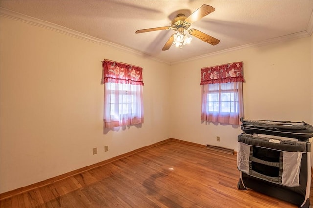 spare room featuring a ceiling fan, crown molding, baseboards, and wood finished floors