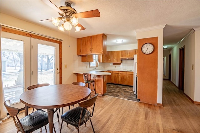 kitchen with a peninsula, light wood finished floors, brown cabinetry, and light countertops