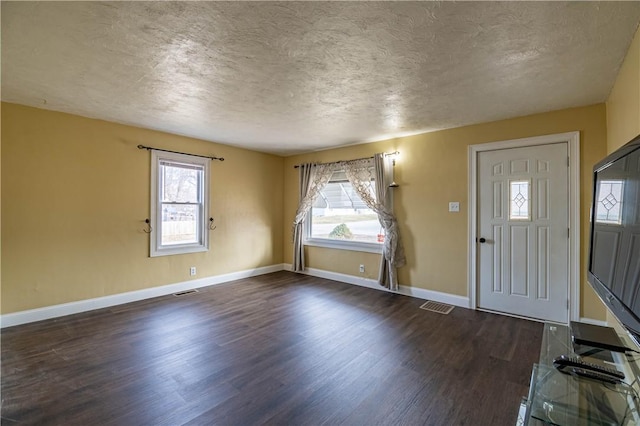 foyer entrance with dark wood-type flooring, a textured ceiling, and plenty of natural light