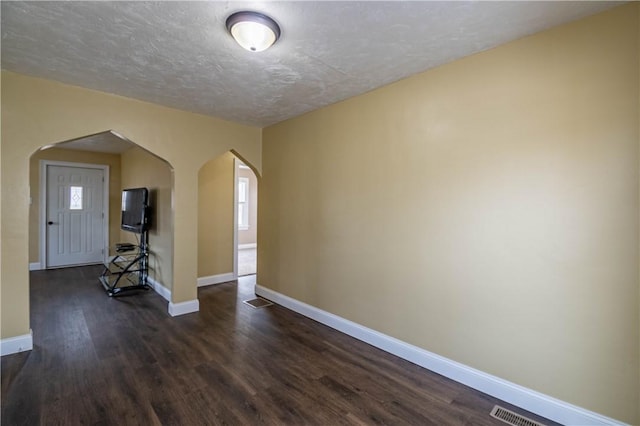 empty room with dark wood-type flooring and a textured ceiling