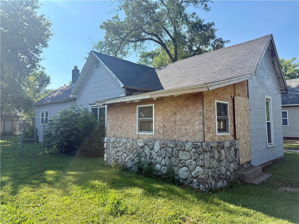 514 Sherman St, Danville, IL 61832 - view of home's exterior featuring a shingled roof, a chimney, and stone siding