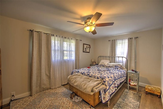 bedroom with baseboards, multiple windows, a ceiling fan, and wood finished floors