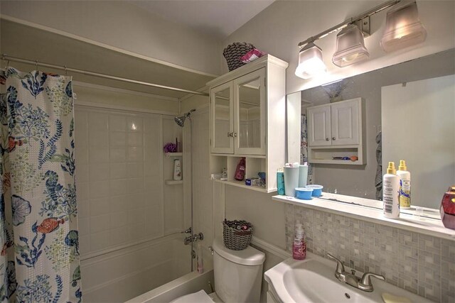 bathroom with a sink, decorative backsplash, toilet, and shower / bath combination with curtain