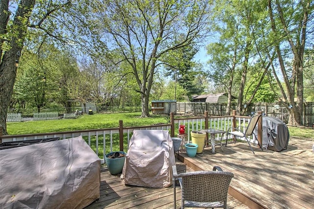 deck featuring a fenced backyard, a storage unit, an outbuilding, and a yard