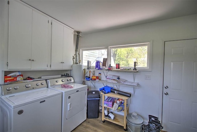 washroom featuring light wood-style floors, cabinet space, gas water heater, and washing machine and clothes dryer