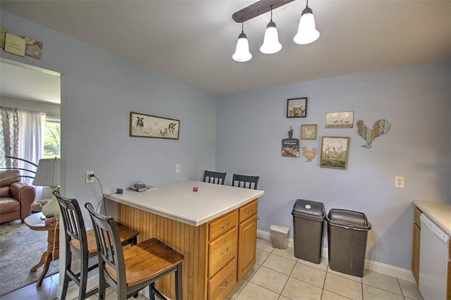 kitchen with light tile patterned floors, a breakfast bar area, a peninsula, and dishwasher