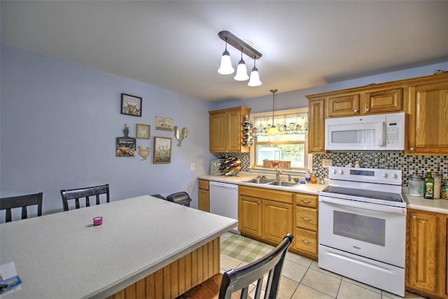 kitchen with tasteful backsplash, brown cabinets, a sink, light countertops, and white appliances