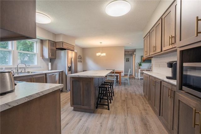 1203 Temple Ave, Effingham, IL 62401 - kitchen with stainless steel appliances, a center island, a kitchen breakfast bar, light wood-style floors, and a chandelier