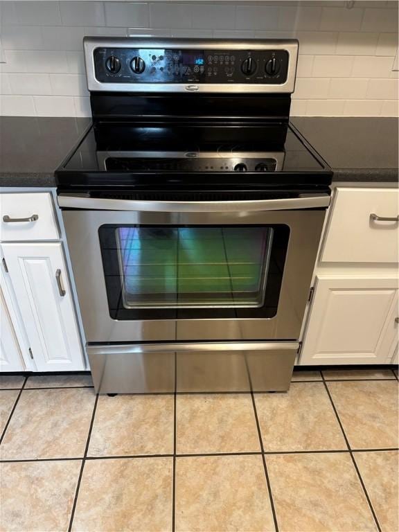 1905 N Vermilion St, Danville, IL 61832 - kitchen with stainless steel electric range, light tile patterned floors, white cabinetry, and backsplash
