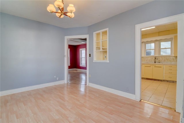 empty room featuring an inviting chandelier, sink, and light hardwood / wood-style floors