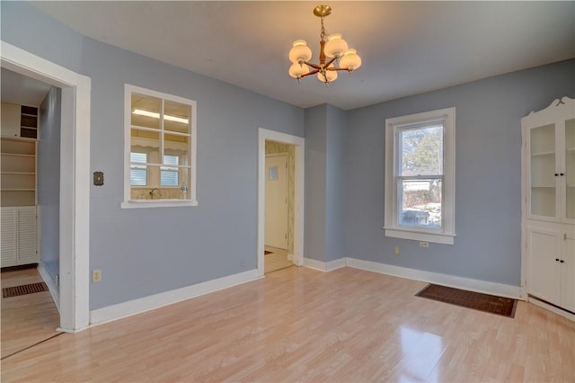 unfurnished dining area with a chandelier and light wood-type flooring