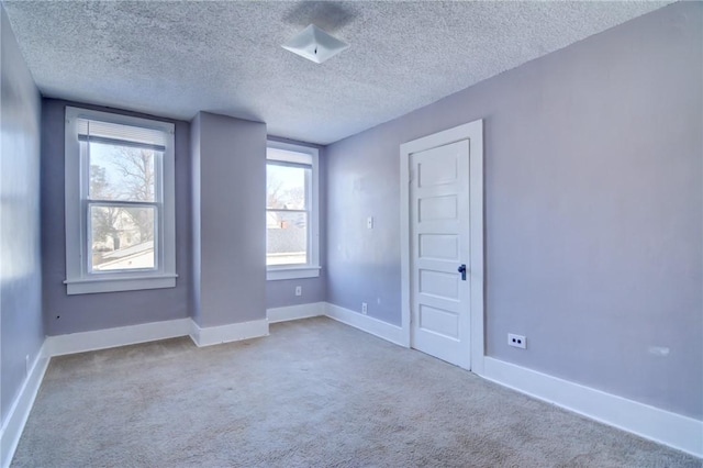 carpeted empty room featuring a textured ceiling