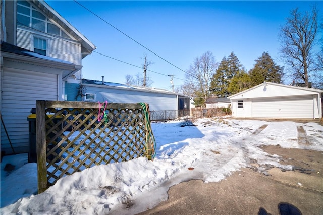 yard layered in snow featuring an outbuilding and a garage