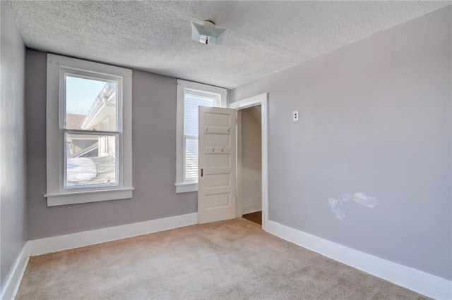 carpeted empty room with a textured ceiling